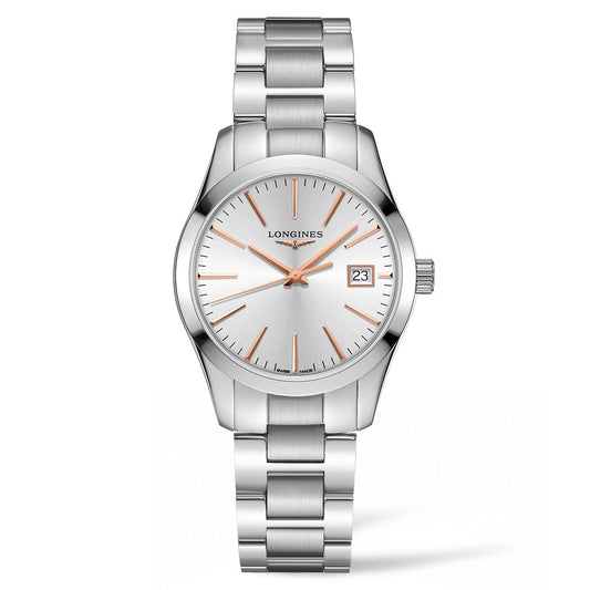 The Longines Conquest Classic Quartz 34mm Watch showcases a sleek silver stainless steel design with a white dial, accented by vibrant orange hour markers and slim orange hands. The iconic Longines brand logo adorns the face, accompanied by a date window at the 3 o'clock position. Its polished metal link bracelet contributes to its timeless elegance.