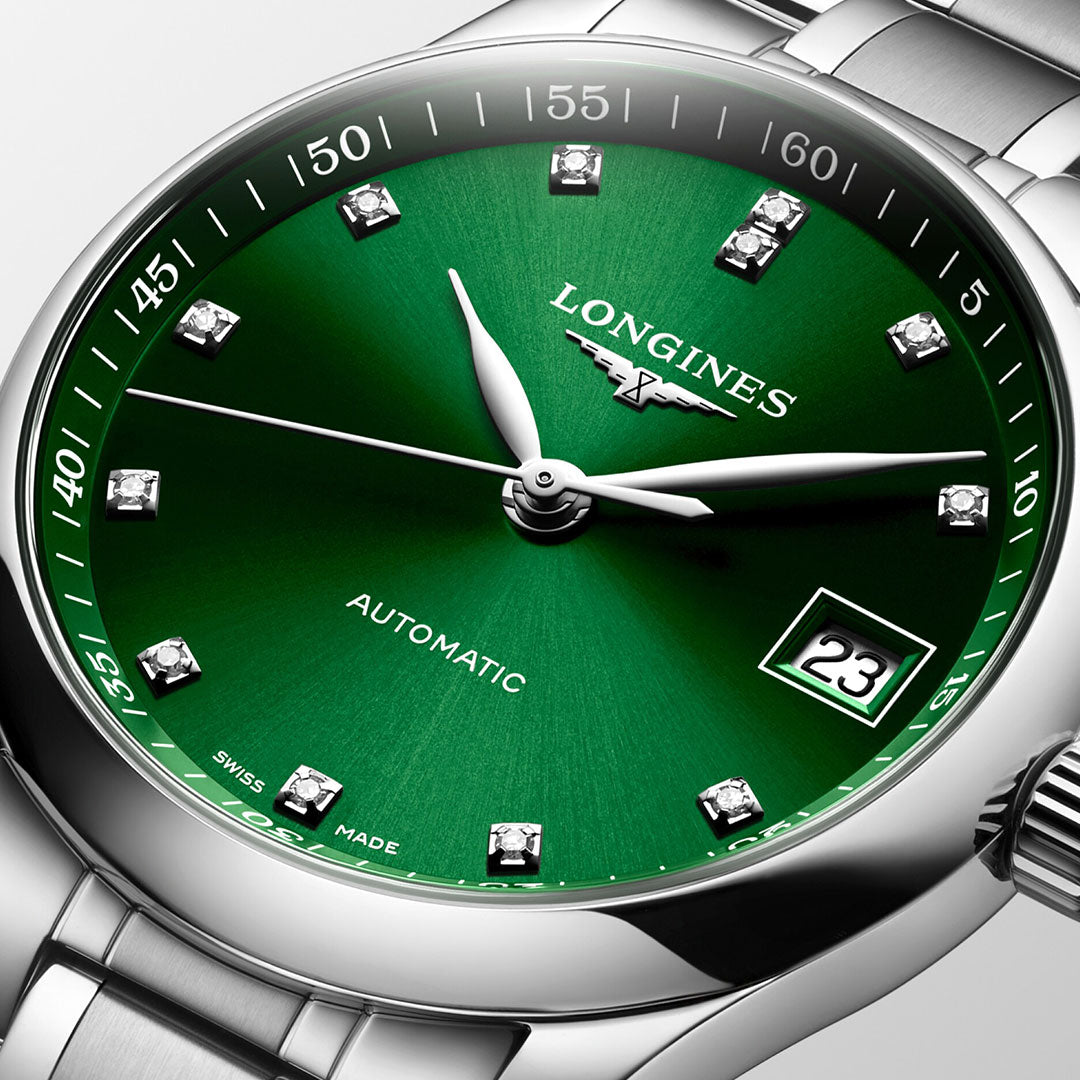 A close-up of the Longines Master Collection Automatic 34mm watch showcases its vibrant green dial. The timepiece, crafted by Longines, features diamond hour markers and a date display at the 3 o'clock position. Embracing traditional watchmaking, its silver hands and minute markers harmonize with the metallic bracelet.