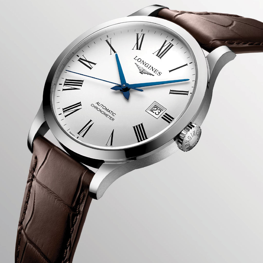 A close-up view of the Longines Record Automatic 40mm Watch exudes classic elegance, showcasing a white dial with Roman numerals and blue hands. It features a silver casing and a brown leather strap, with the date window on the right. The brand name "Longines" graces the dial, highlighting its refined charm.