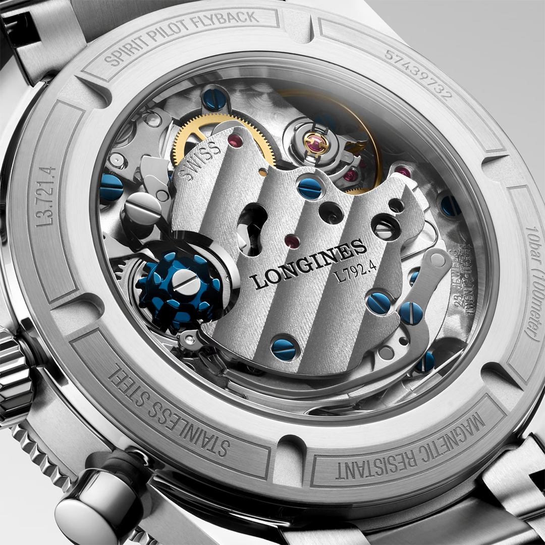 Close-up view of a Longines Spirit Pilot Flyback Automatic Manual Winding 39.5mm Watch movement through a transparent case back, showing intricate mechanical gears, springs, and a central plate engraved with “LONGINES L792.4.”