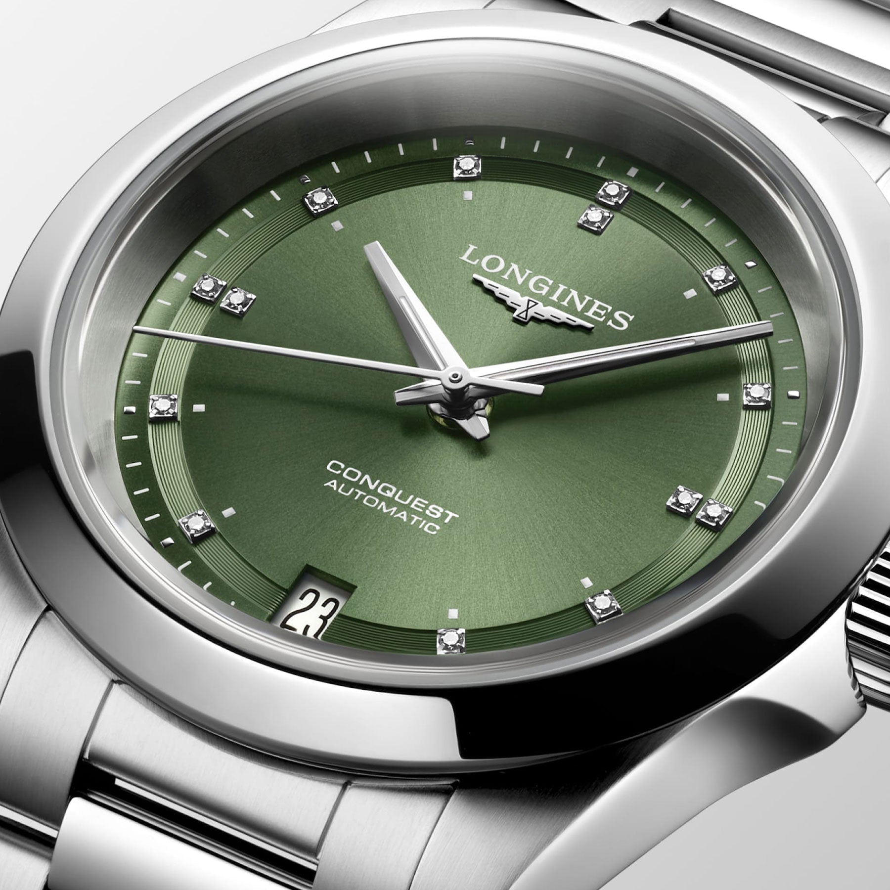 A close-up of the Longines Conquest Automatic 34mm Watch highlights its elegance with a green dial, silver hour markers, and diamond accents. This Longines timepiece underscores performance with a date display at 3 o'clock and a sturdy stainless steel case and bracelet.