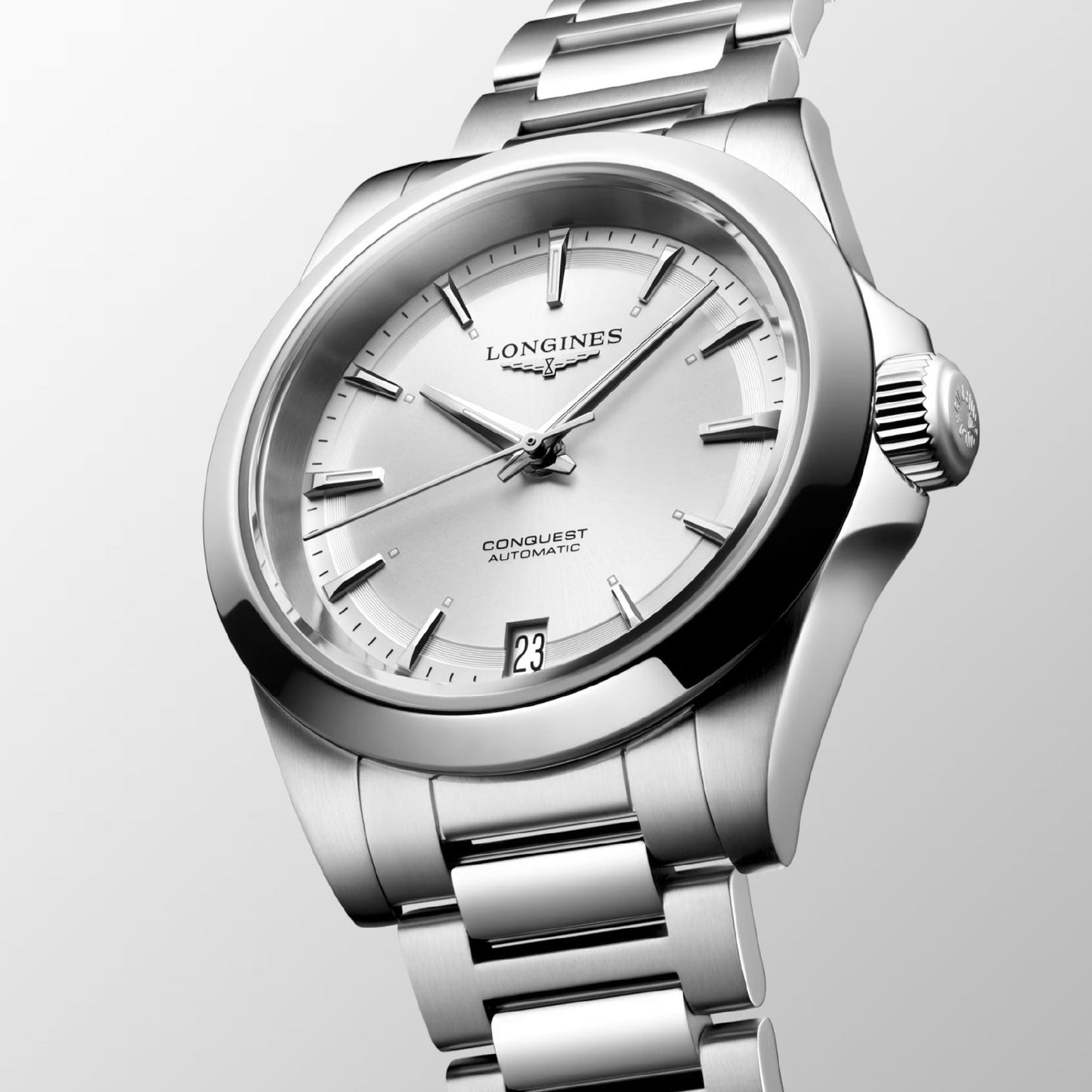 The Longines Conquest Automatic 34mm Watch is an elegant timepiece featuring a metal link bracelet and a white dial, epitomizing Longines' dedication to timeless performance. Silver hour markers complement the date display at 3 o'clock, while the Longines logo adorns the textured crown for a secure grip.