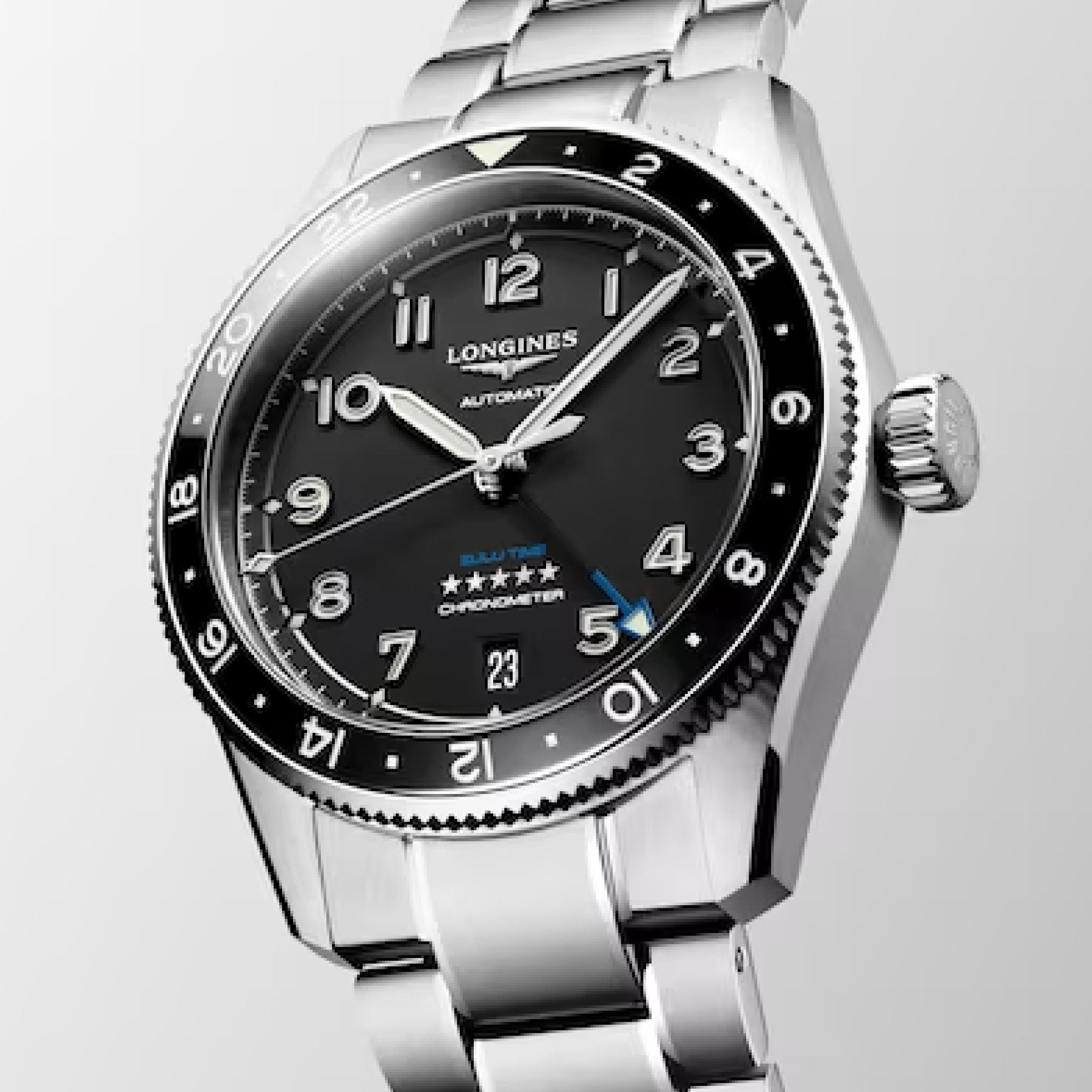 The Longines Spirit Zulu Time Automatic COSC 39mm Watch by Longines features a black dial with white hour markers and a date display at the 6 o'clock position. It boasts a silver bezel with 24-hour indicators, all elegantly set on a metallic bracelet.