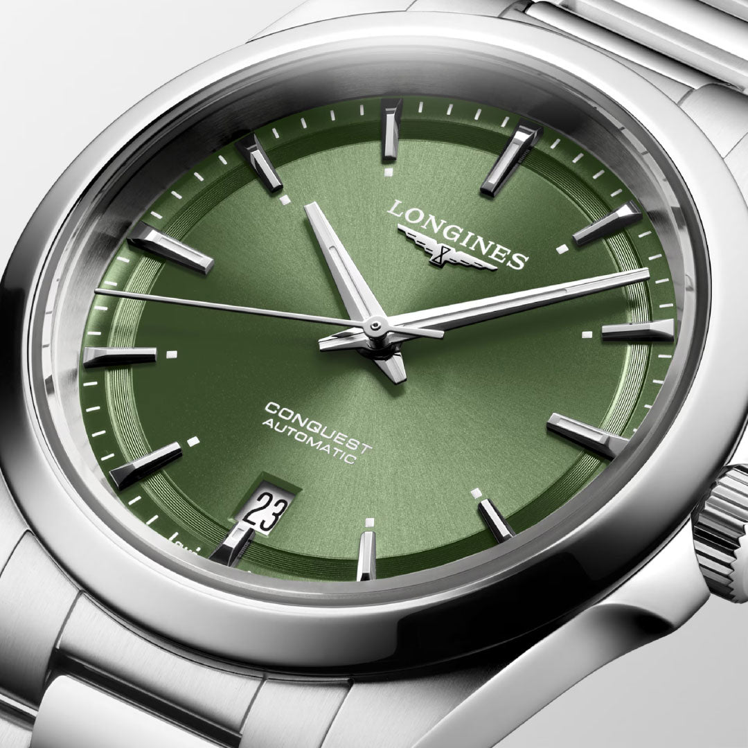 A close-up of the Longines Conquest Automatic 38mm Watch, featuring a metallic green dial, Swiss Super-LumiNova® markers and hands, date display at 6 o’clock, and a water-resistant stainless steel bracelet.