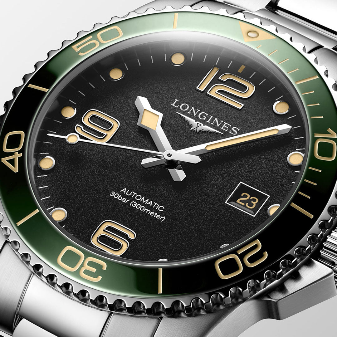 Close-up of the Longines HydroConquest Automatic 41mm Watch, showcasing a black dial with striking gold numerals and a green bezel. This Longines timepiece features a date display and comes with a stainless steel band. It offers water resistance up to 300 meters.