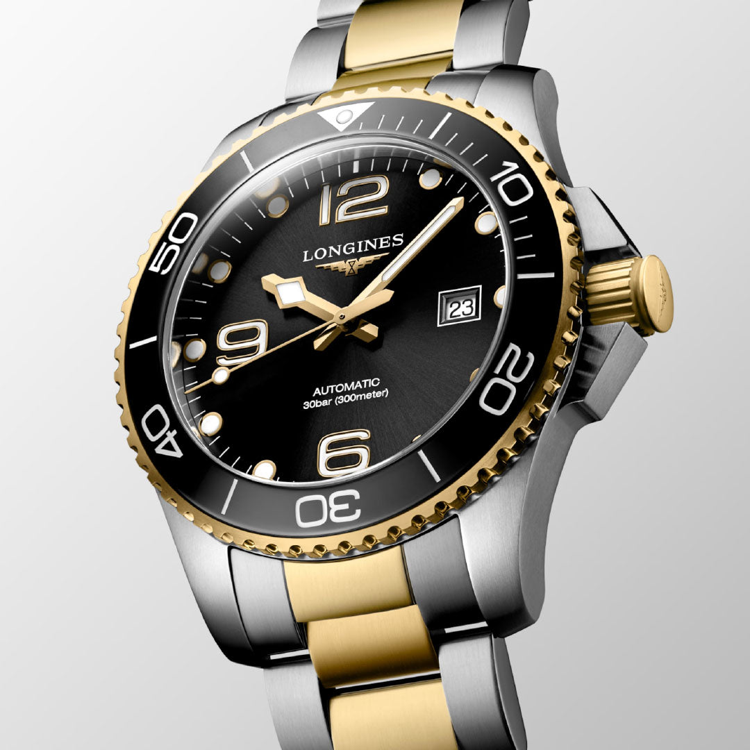A close-up of the Longines Hydroconquest Automatic 43mm Watch featuring a black and gold unidirectional bezel, gold crown, black dial with gold accents, date display, luminous hands and numbers, and a silver-gold metal strap.
