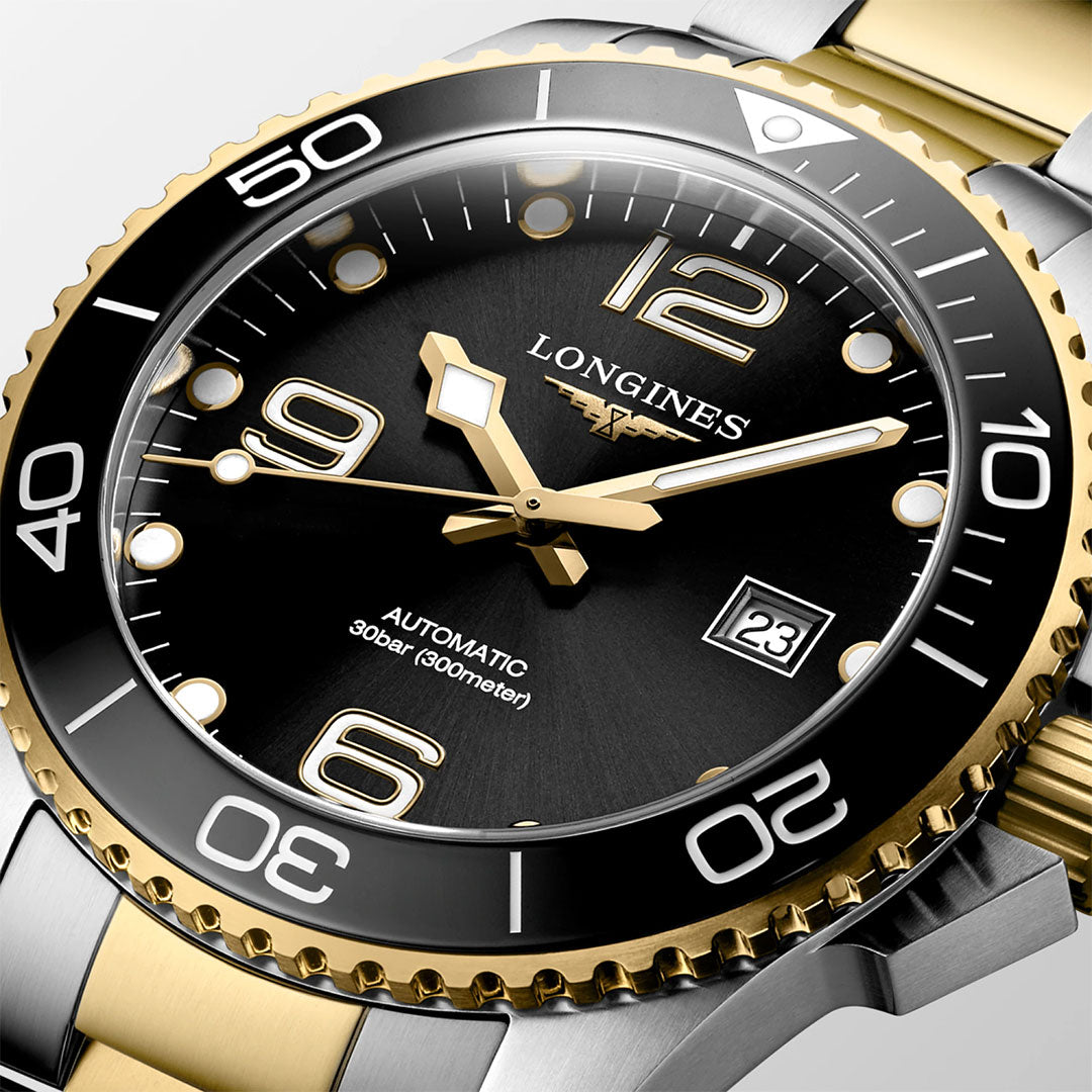 A close-up of the Longines Hydroconquest Automatic 43mm Watch, featuring a black dial, gold and silver accents, luminous hands and markers, unidirectional bezel, date window at 3 o’clock, and marked "AUTOMATIC 30 bar (300m/1000ft)".