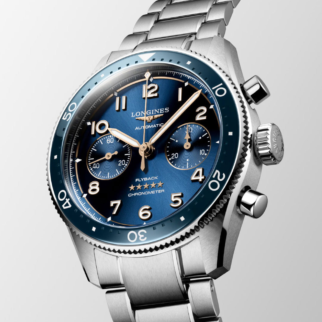 The Longines Spirit Flyback Automatic Chronograph 42mm Watch showcases a striking blue dial with three subdials and an automatic chronometer. It features a minute-marked bezel and prominent numerals alongside the renowned winged hourglass emblem of the Longines brand. This classic design is finished with a polished metal bracelet, making it an enduring masterpiece from Longines.