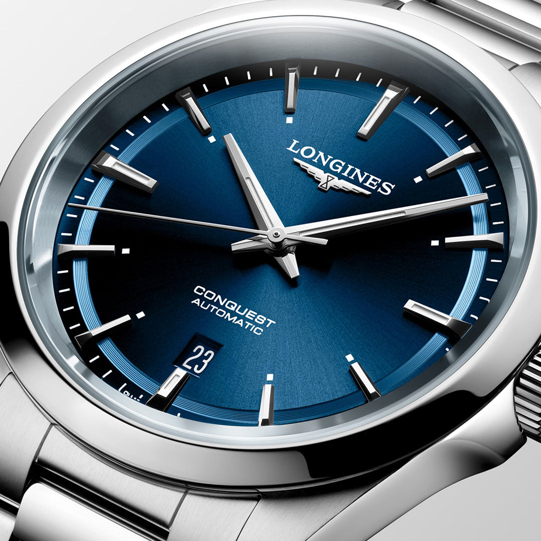 The Longines Conquest Automatic 41mm Watch exudes elegance with its stainless steel design, featuring a blue face and silver hour markers. This timepiece seamlessly combines performance by displaying the date at the 3 o'clock position. The silver hands stand out against the deep blue dial, while the polished steel link bracelet contributes a sleek touch to the overall aesthetic.