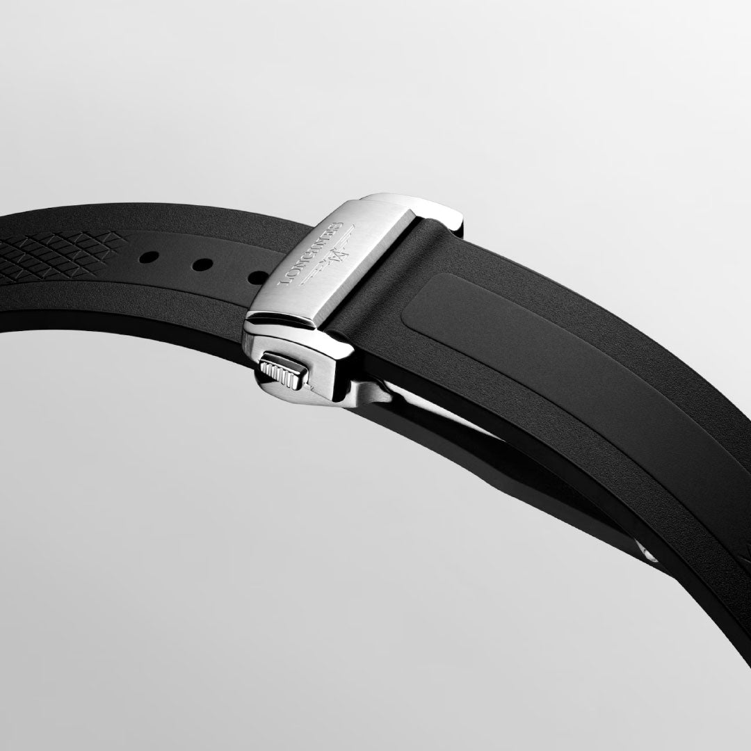 A close-up of the Longines Conquest Chronograph Automatic 42mm Watch by Longines, showing its black rubber strap, polished silver clasp, and scratch-resistant sapphire crystal on a light gray background.