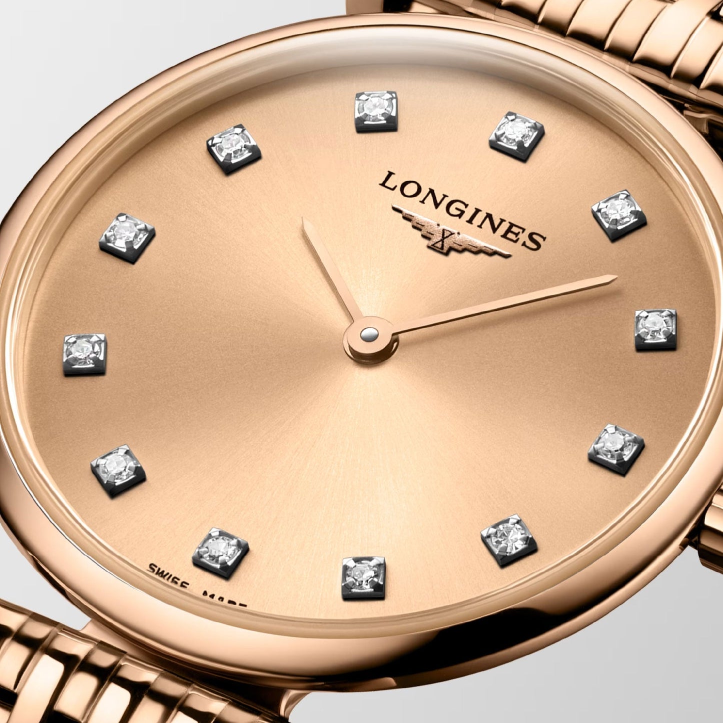 A close-up of the Longines La Grande Classique De Longines Quartz 24mm Watch highlights its gold-tone dial adorned with diamond hour markers and elegant gold hands. Exuding timeless sophistication, this piece features a matching gold bracelet and prominently displays the Longines logo beneath the 12 o'clock mark.