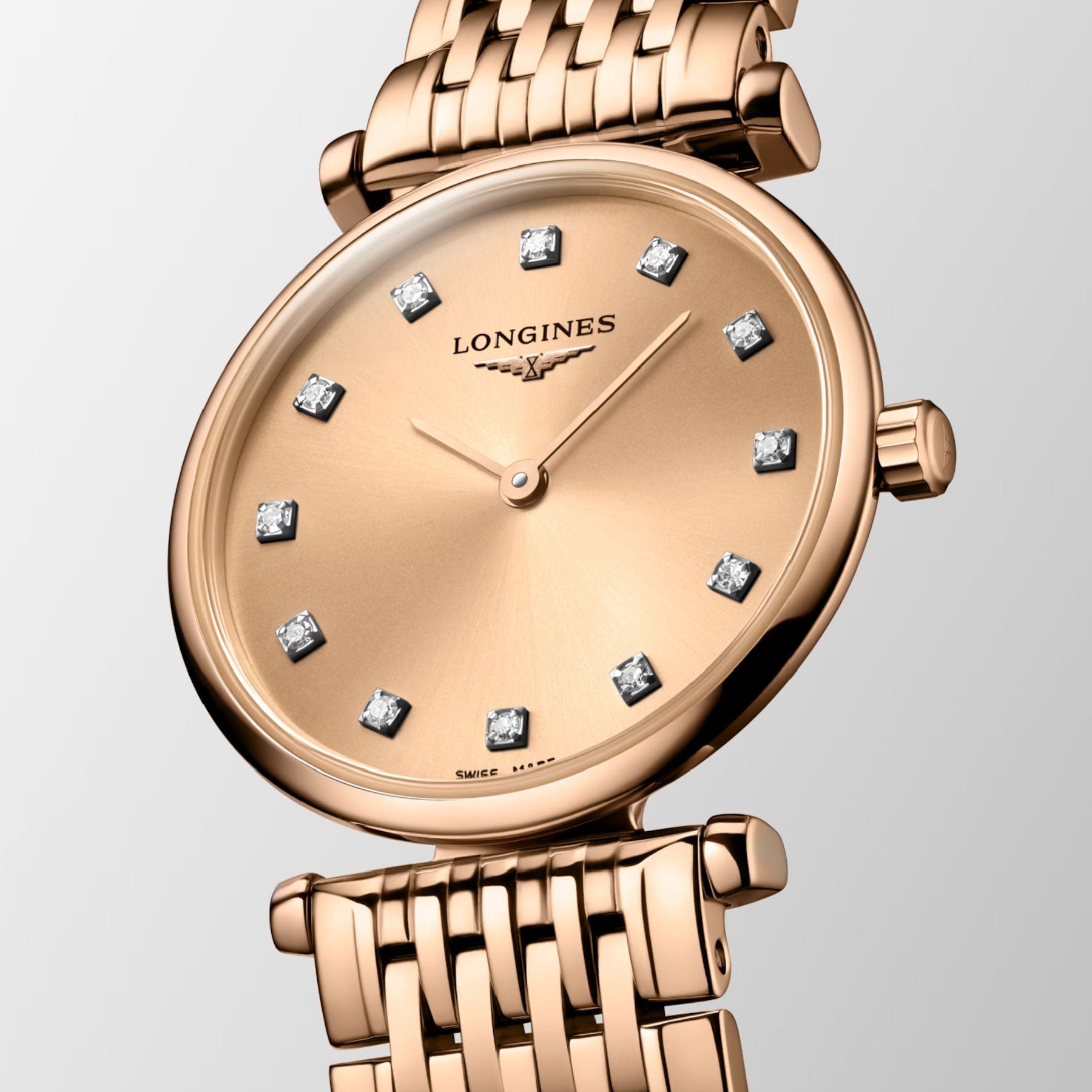 The Longines La Grande Classique De Longines Quartz 24mm Watch with its gold bracelet radiates classic elegance. It features a gold face adorned with diamond hour markers and sleek gold hands, set against a plain off-white background, capturing timeless sophistication in every detail.