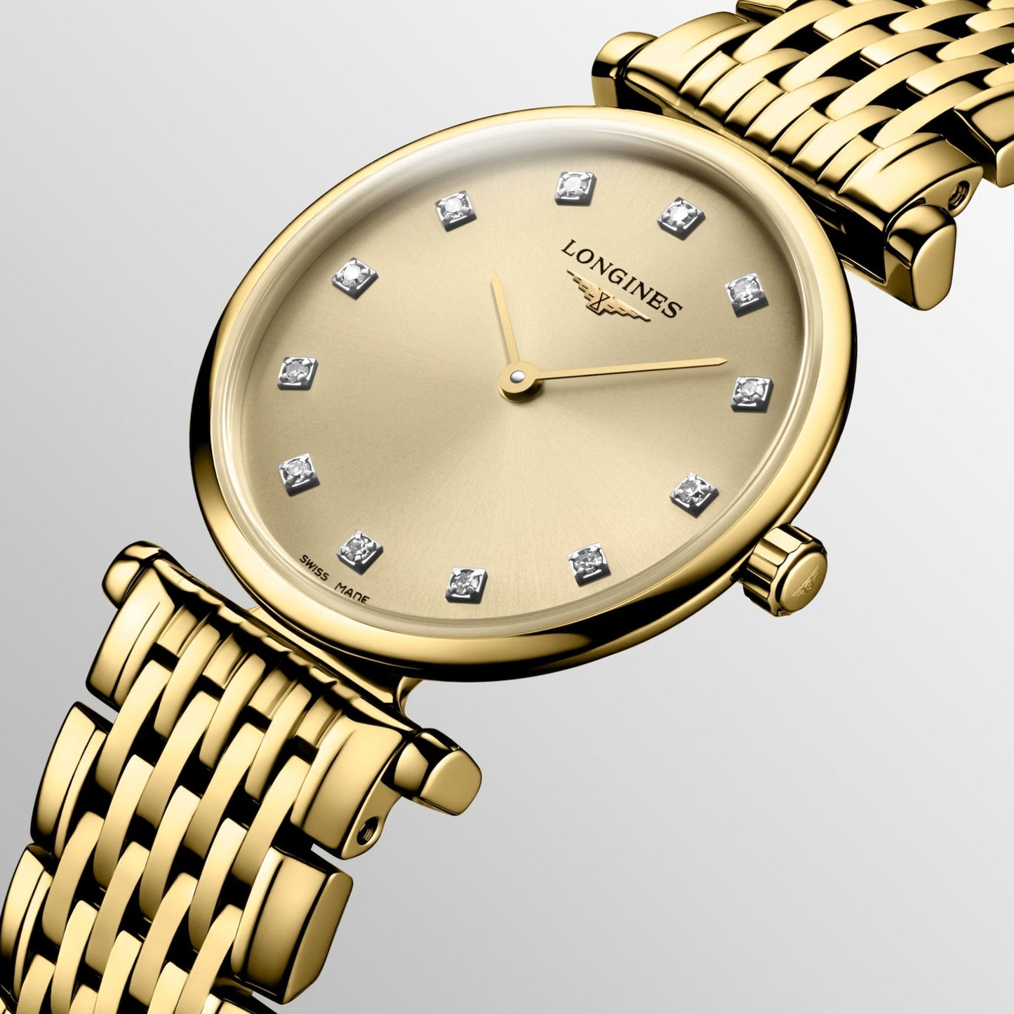 This close-up features the Longines La Grande Classique De Longines Quartz 24mm Watch, epitomizing classic elegance. Its woven band harmonizes with the gold face adorned with diamond hour markers. The simple, elegant hands glide gracefully, embodying timeless sophistication against the metallic backdrop.