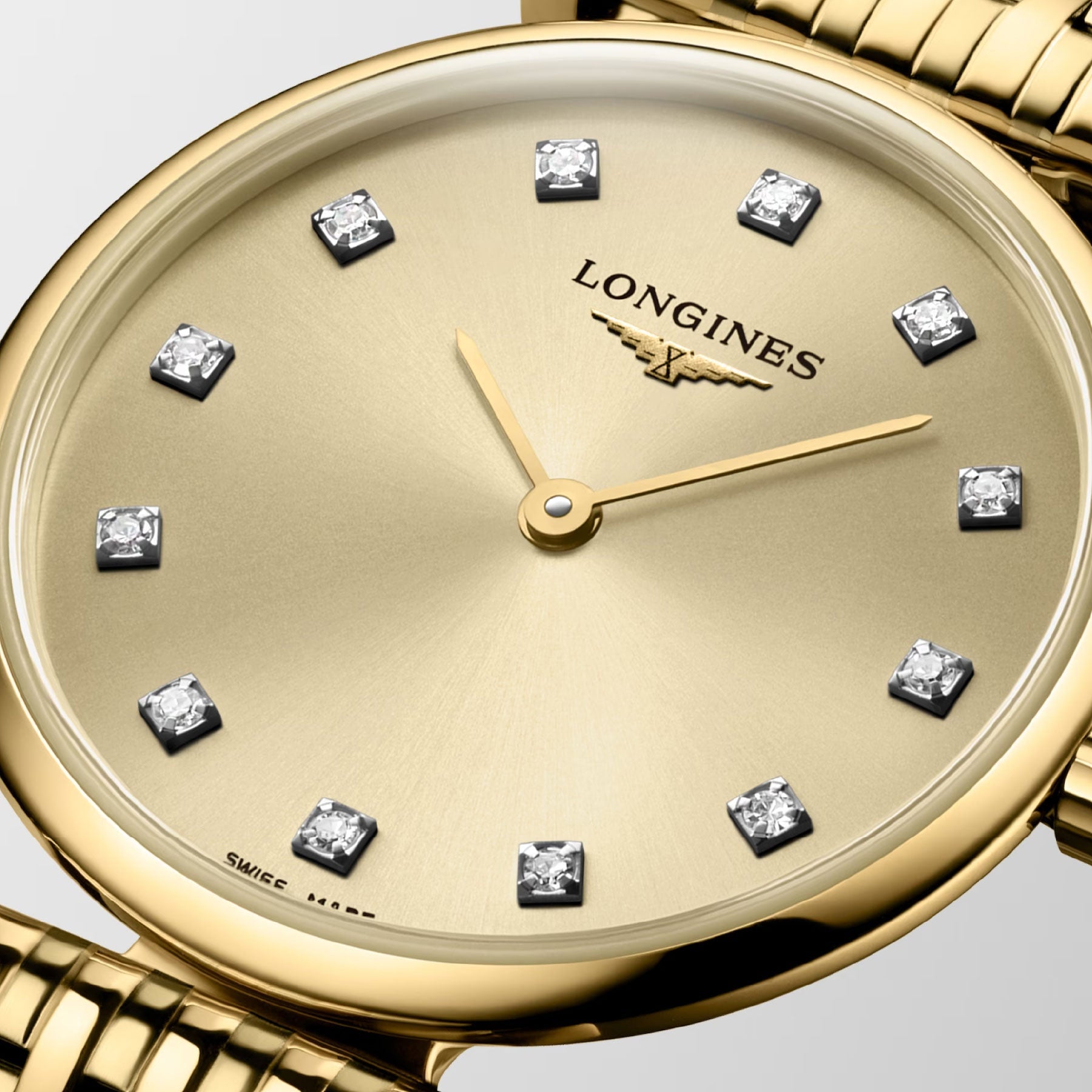 The Longines La Grande Classique De Longines Quartz 24mm Watch exudes timeless sophistication with its gold design. The round face features a champagne-colored dial adorned with diamond hour markers and gold hands. Complemented by a gold bracelet, the watch is elegantly finished with the iconic Longines logo positioned below the 12 o'clock mark.