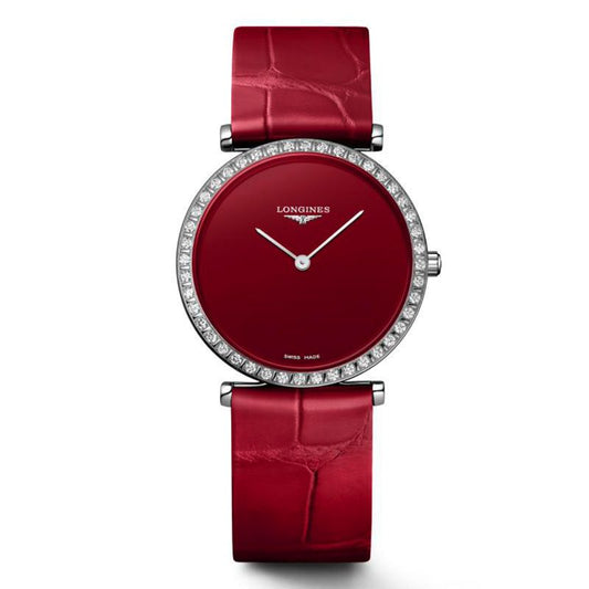 The Longines La Grande Classique Quartz 29mm Watch exudes classic elegance with its luxurious red leather strap and matching face. Its slim design is accentuated by a diamond-studded bezel, complemented by elegant silver hands and a scratch-resistant sapphire crystal. The brand name "Longines" is prominently displayed beneath the 12 o'clock position.