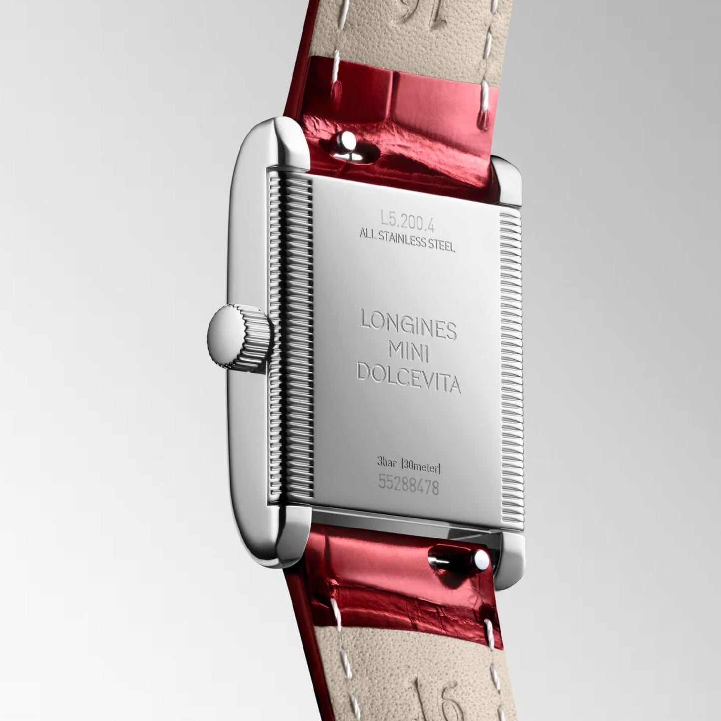 The Longines Mini Dolcevita Quartz 21.5 x 29mm watch showcases a silver stainless steel case back engraved with "Longines Mini DolceVita," complemented by a red leather strap. The timepiece is designed with a grooved edge and features a crown on the left side, all set against a plain grey background.