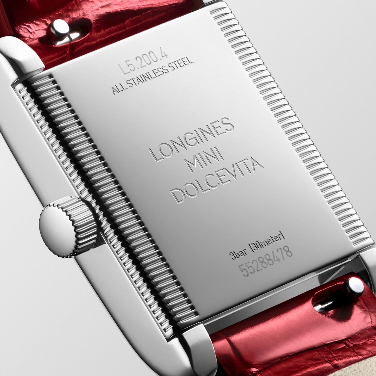 Close-up of the back of a Longines Mini Dolcevita Quartz 21.5 x 29mm watch. The polished stainless steel case displays the model number, material information, and water resistance details. Paired with a vibrant red leather strap, this elegant timepiece embodies timeless sophistication.