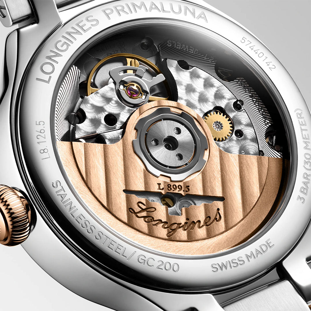 Close-up of the Longines Primaluna Moonphase Automatic 34mm watch back, highlighting its detailed mechanical movement, silver and gold tones, engraved Longines branding, plus "Swiss Made" and "Stainless Steel" on the rim.