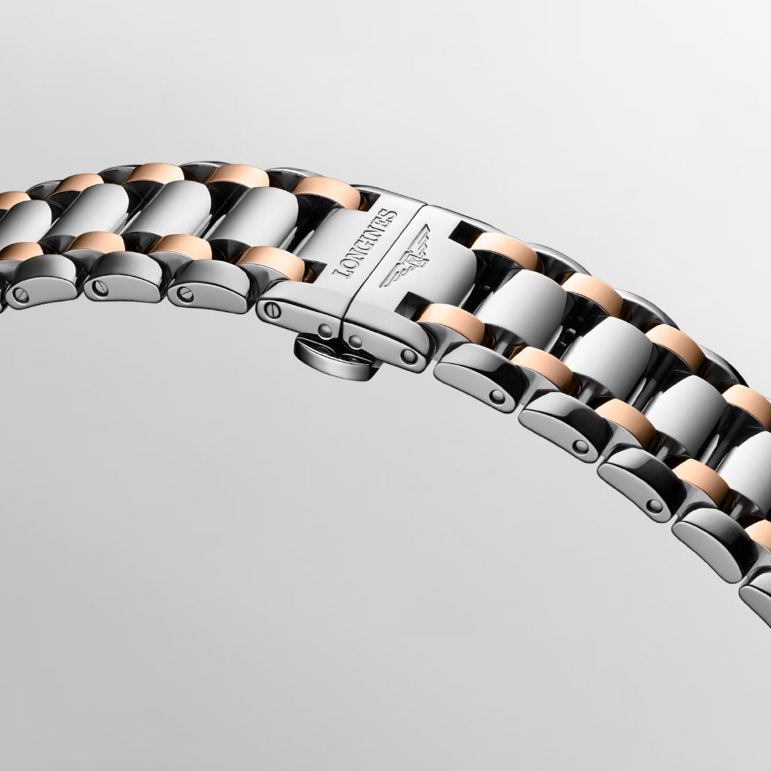 A close-up of the Longines Primaluna Moonphase Automatic 34mm Watch bracelet in silver and rose gold, showcasing the engraved Longines logo on the clasp against a light gray background.