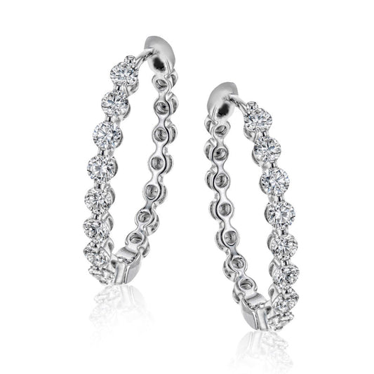 The Simon G. 18K White Gold Diamond Hoop Earrings exude elegance as they are embellished with shimmering white diamonds, thoughtfully arranged along the hoop. This design offers a luxurious and refined look, ideal for sophisticated occasions, all set against a plain white background.