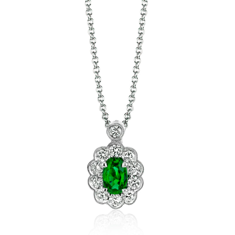 The Simon G. 18K White Gold Tempera Diamond And Emerald Necklace Pendant features an elegant design with a central oval emerald, encircled by beautifully detailed round white diamonds, all suspended from a delicate chain.