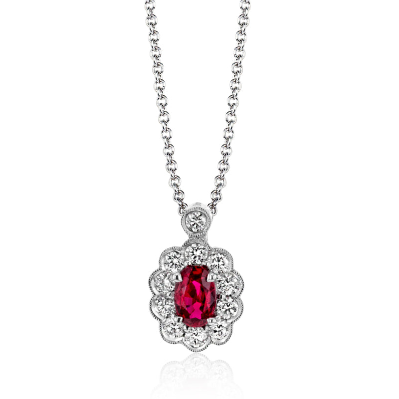 The Simon G 18K White Gold Diamond with Ruby Necklace Pendant features a pendant with a dazzling patterned design, highlighting an oval ruby encircled by smaller clear stones, all beautifully set in an intricate, decorative frame.