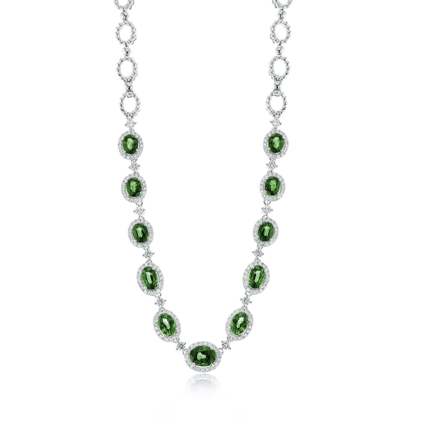 The Simon G 18K White Gold Emerald and Diamond Necklace is an exquisite piece featuring oval-shaped emerald-like green gemstones encircled by small, clear diamonds. The chain, adorned with clear stones, is crafted from premium 18k white gold and elegantly displayed against a pristine white backdrop.