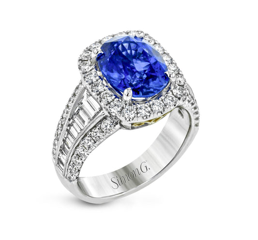 The Simon G. 18K White Gold Sapphire with Diamond Ring is an exquisite piece from the renowned brand Simon G, featuring a stunning oval sapphire encircled by a brilliant halo of small diamonds. The engraved band, adorned with additional shimmering diamonds, embodies elegance and sophistication, making it a timeless treasure.