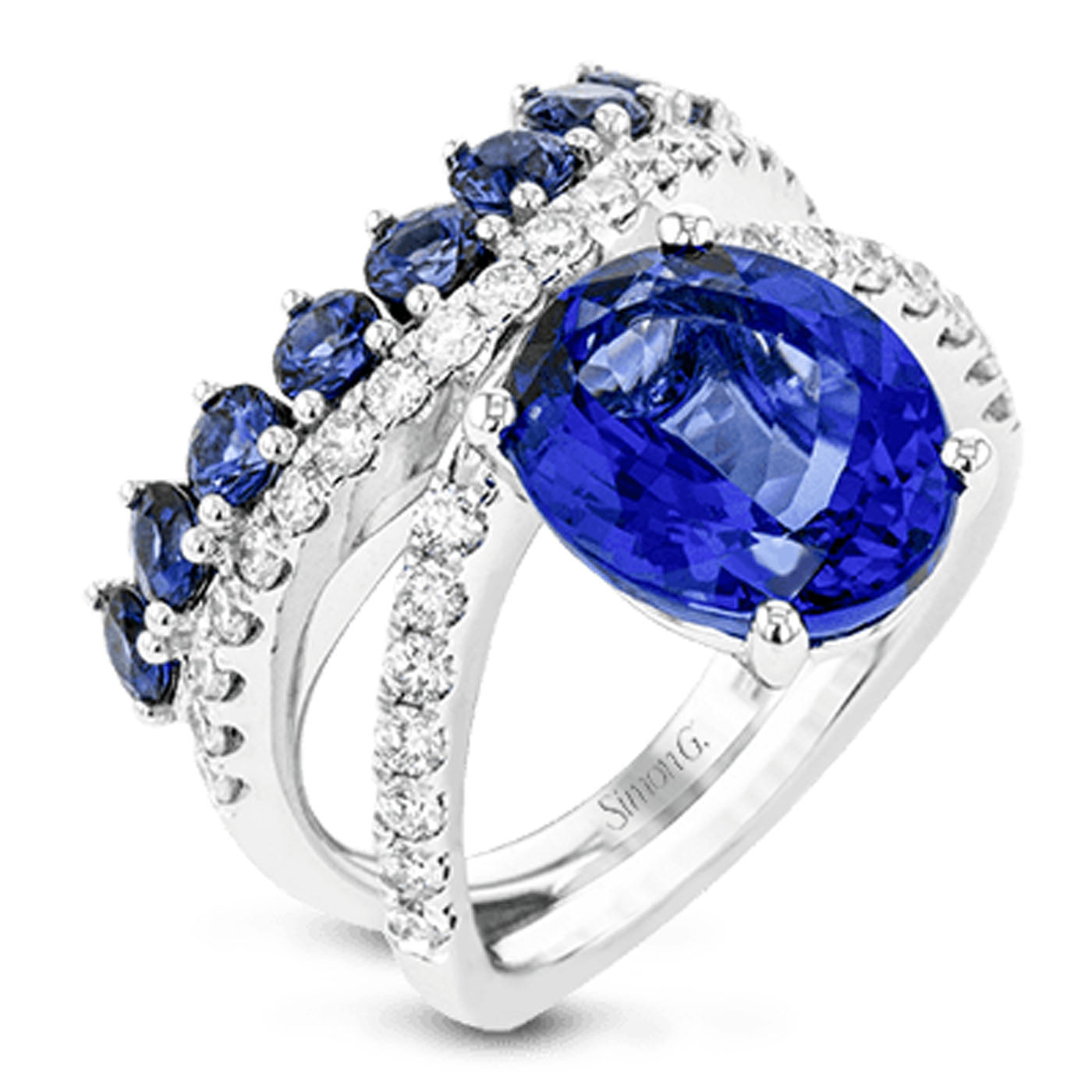 The Simon G. 18K White Gold Oval Tanzanite with Diamond and Sapphire Fashion Ring offers an elegant layered design, showcasing a large oval tanzanite gemstone at the center, complemented by smaller sapphires on one band and a row of white diamonds on another.