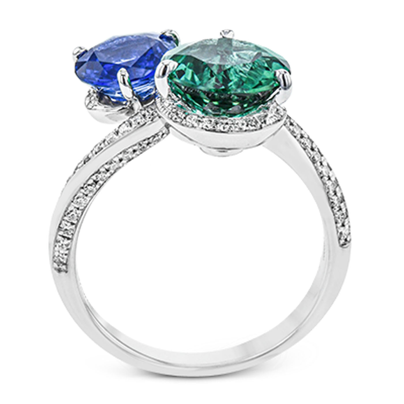 Introducing the Simon G. 18K White Gold Tourmaline and Sapphire with Diamond Ring: a striking piece designed by Simon G, featuring two magnificent oval gemstones. One gemstone is a captivating blue sapphire, complemented perfectly by a vivid green tourmaline, both set side by side. The elegant band is exquisitely adorned with small, sparkling white diamonds for an added touch of luxury.