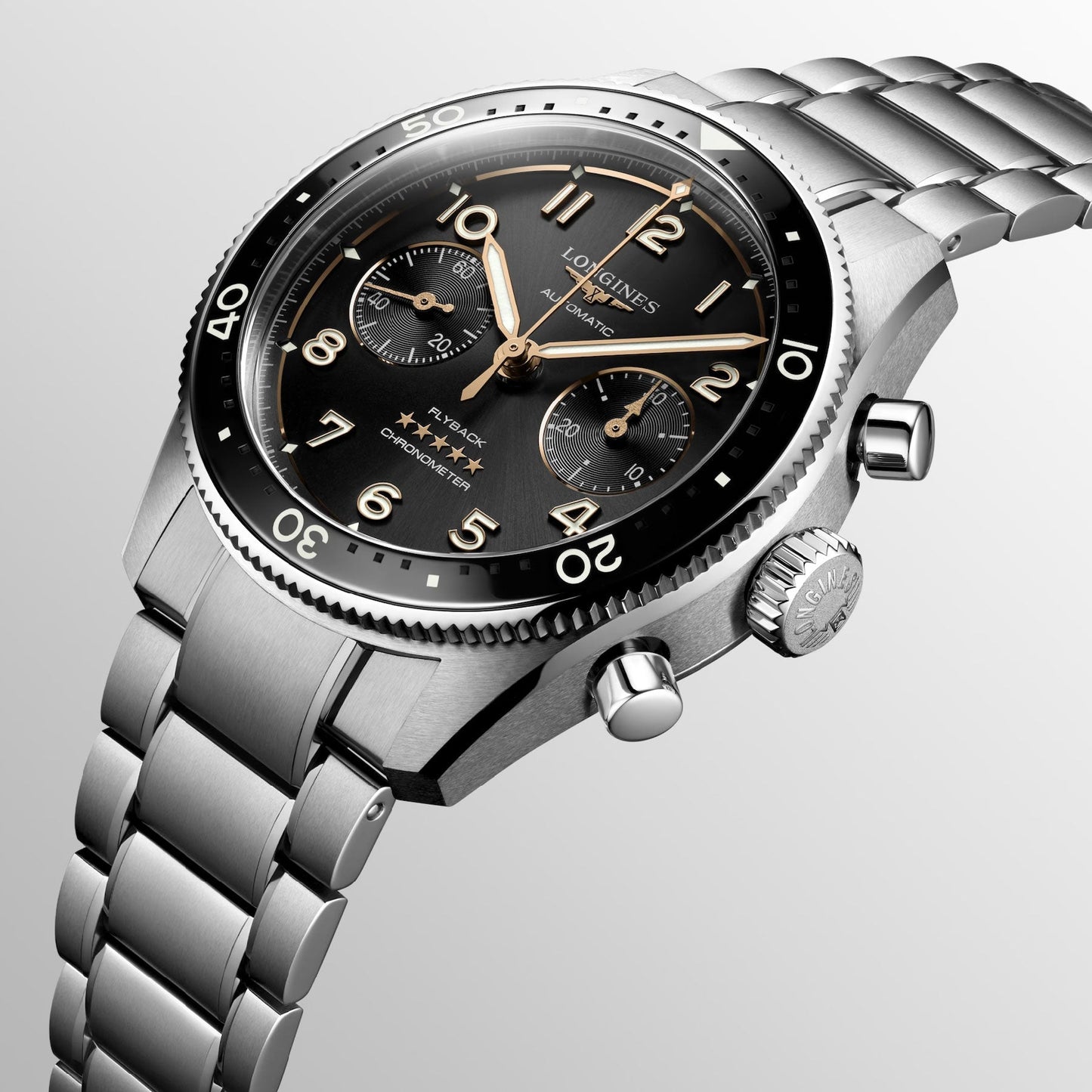 Introducing the Longines Spirit Flyback Automatic Chronograph 42mm Watch, a luxurious stainless steel timepiece featuring a black bezel and dial, embellished with three subdials and striking gold hands. This exquisite watch from Longines encapsulates the timeless elegance of legendary pioneers and is elegantly showcased on a light gray background.