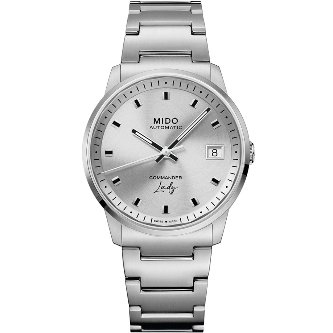 The MIDO Commander Lady Automatic 35mm Watch features a round silver dial, black hour markers, date window at 3 o’clock, metallic bracelet, and minimalistic design—a refined Swiss luxury watch for women.