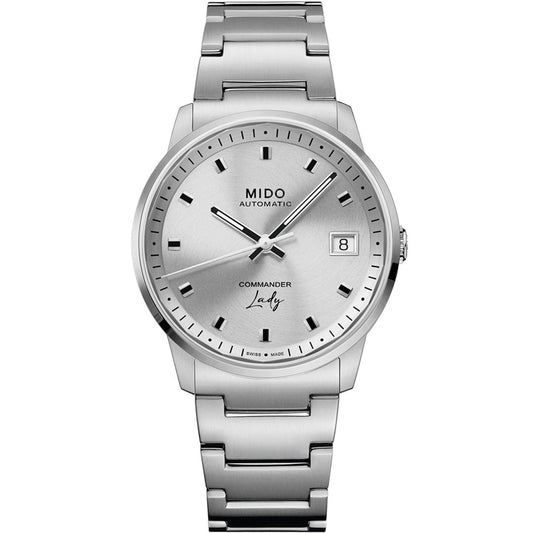 The MIDO Commander Lady Automatic 35mm Watch features a round silver dial, black hour markers, date window at 3 o’clock, metallic bracelet, and minimalistic design—a refined Swiss luxury watch for women.
