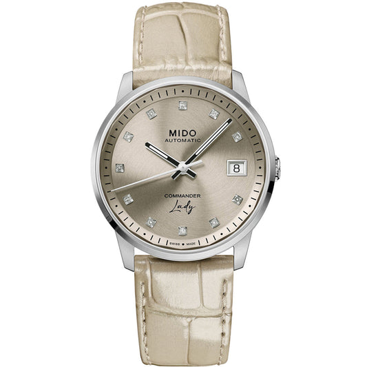 The MIDO Commander Lady Automatic 35mm Watch features a beige leather strap, silver round face, diamond hour markers, date at 3 o’clock, and "MIDO" branding on the dial.
