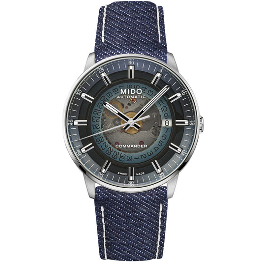 The MIDO Commander Gradient Automatic 40mm Watch features a transparent acrylic dial with blue accents, visible gears, day/date indicators, “MIDO COMMANDER” text, a blue fabric strap, round silver case, and Caliber 80 movement.