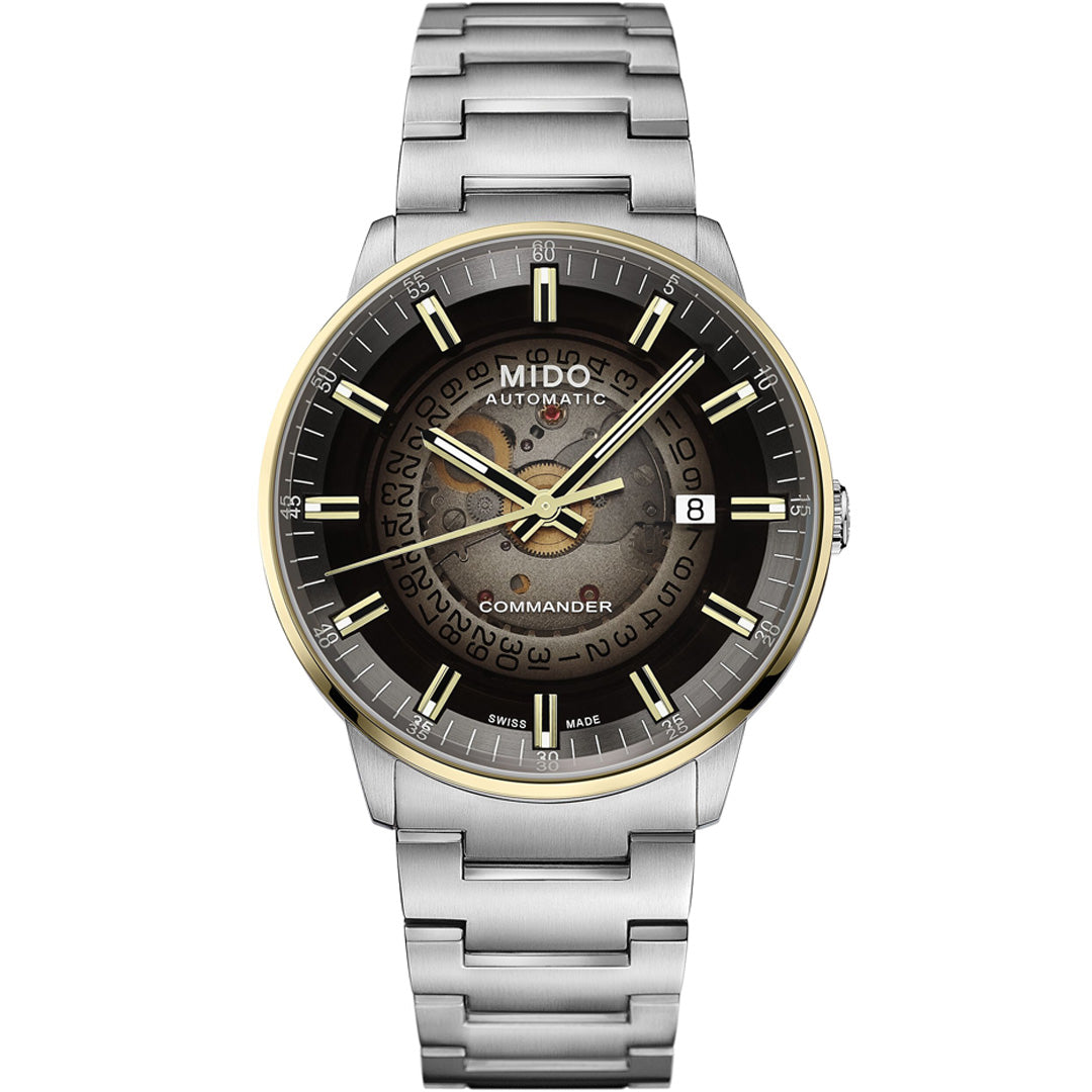The MIDO Commander Gradient Automatic 40mm Watch features a gold-tone bezel, date at 3 o’clock, stainless steel bracelet, and a transparent acrylic dial revealing the Caliber 80 movement.