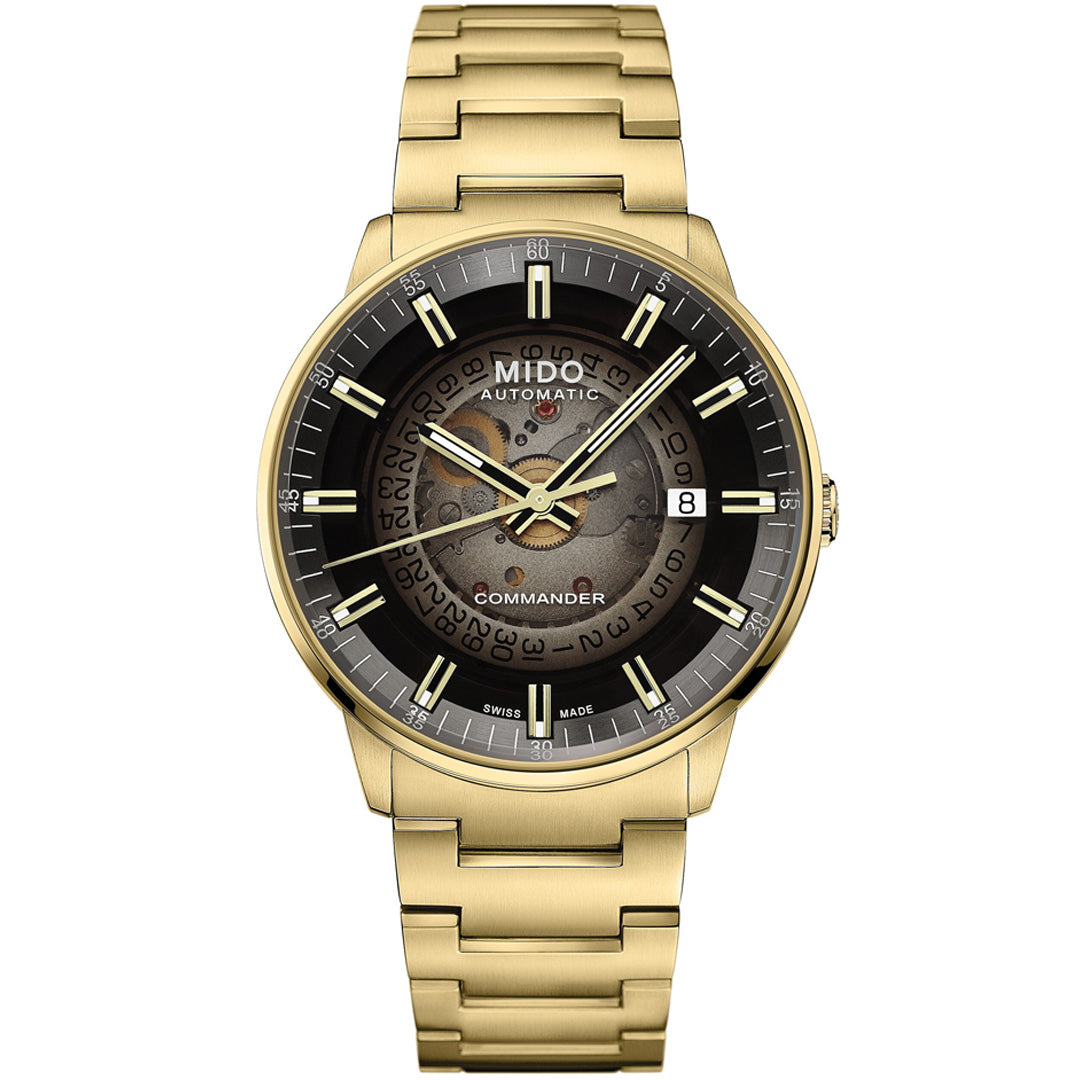The MIDO Commander Gradient Automatic 40mm Watch features a gold finish, transparent acrylic dial with black and gold details, Caliber 80 movement, date at 3 o'clock, Swiss Made text, skeleton face revealing gears, and a matching gold bracelet.