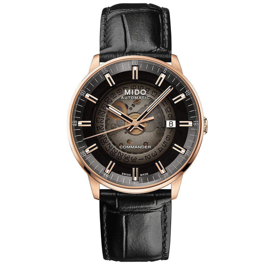 The MIDO Commander Gradient Automatic 40mm Watch features a black leather strap, rose gold case, transparent dial revealing the Caliber 80 movement, metallic accents, and a date window at 3 o’clock.