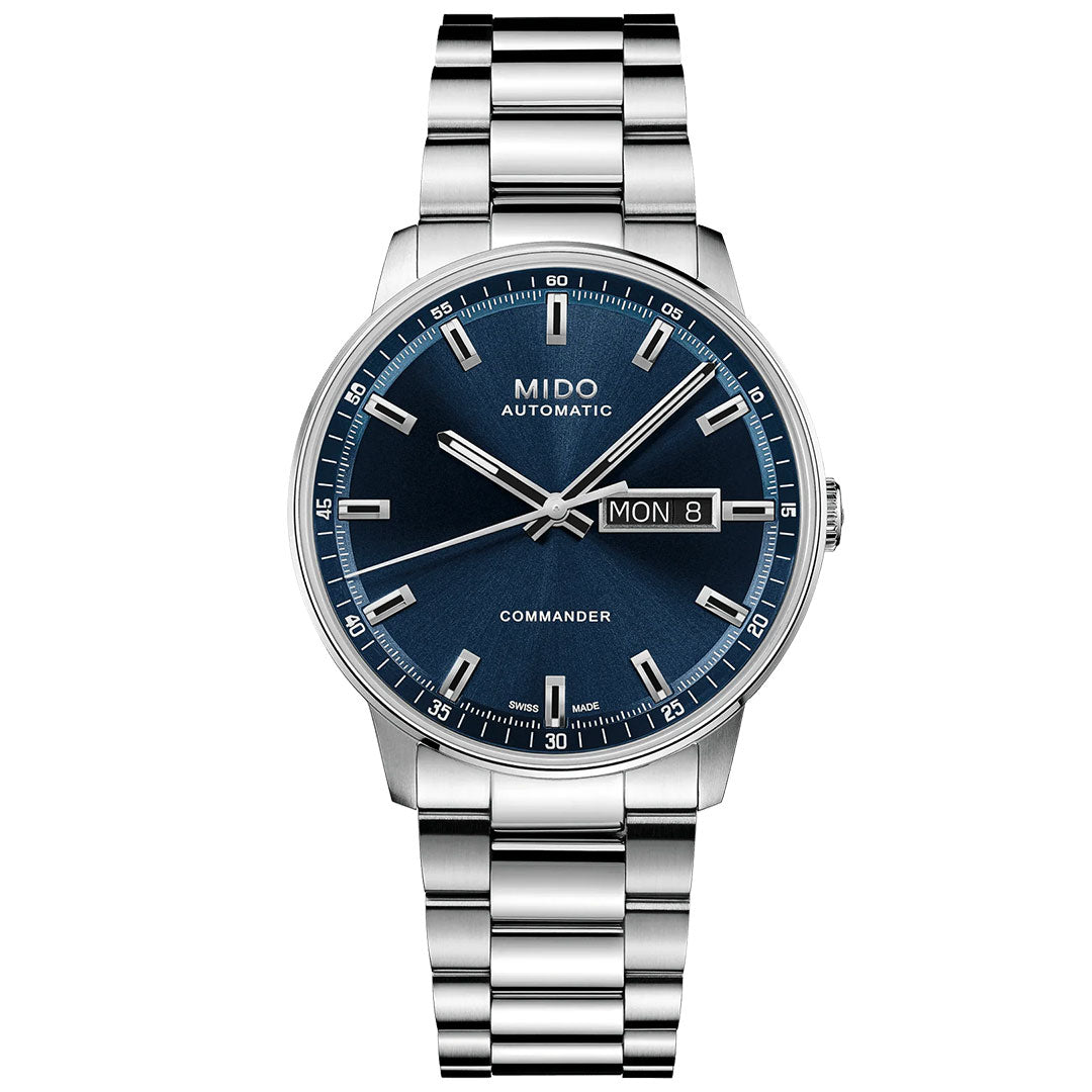 The MIDO Commander Datoday Automatic 40mm watch features a blue dial, silver hour markers, day-date display at 3 o'clock, and a stainless-steel link bracelet.