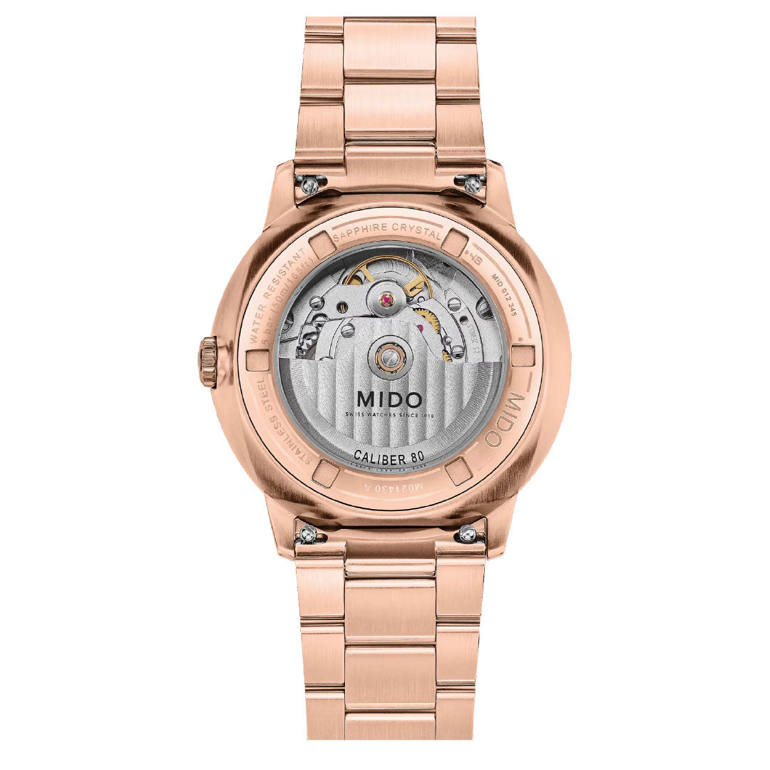 Back view of the MIDO Commander Datoday Automatic 40mm shows a rose gold stainless steel watch with transparent case back, visible Caliber 80 movement, engraved details, metal bracelet, and a rotor marked "MIDO" and "Caliber 80".