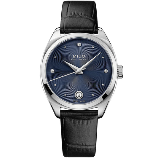 The MIDO Belluna Royal Lady Automatic 33.4mm Watch features a dark blue sunburst dial, silver hour markers, date window at 6 o’clock, black leather strap, and a sleek silver case for a refined minimalist look.