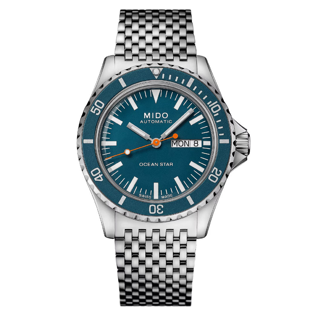 The MIDO Ocean Star Tribute Automatic 40.5mm watch features a silver-tone design with a blue dial, silver hour markers, day/date display at 3 o'clock, stainless steel bracelet, rotating bezel, and Caliber 80 automatic movement.