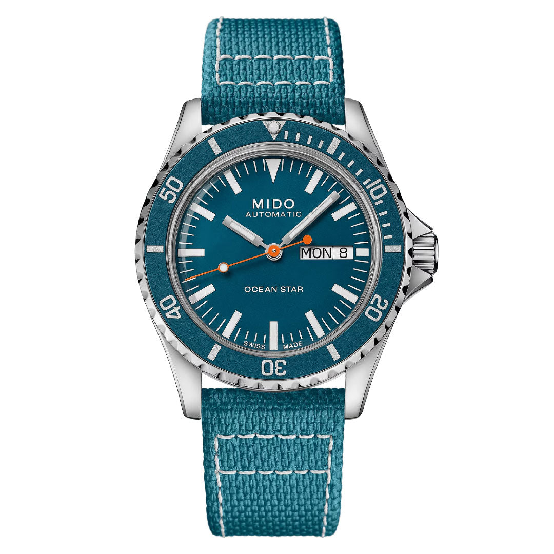 The MIDO Ocean Star Tribute Automatic 40.5mm Watch features a Caliber 80 movement, teal fabric strap, teal dial with white markings, orange hand accents, and a day-date display at 3 o’clock.