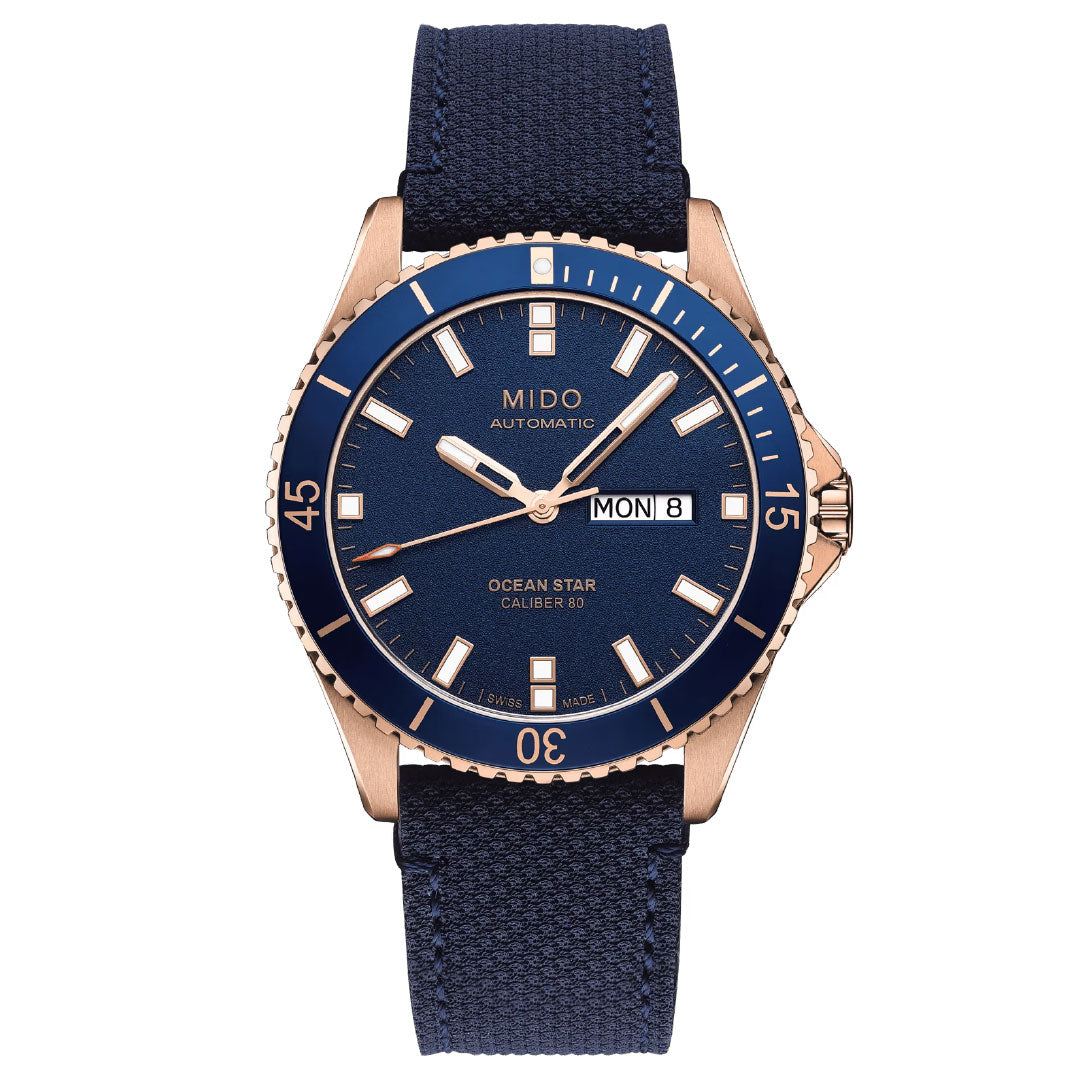 The MIDO Ocean Star 39mm Automatic Watch features a blue face, blue bezel, blue fabric strap, rose gold case, day-date display, luminous markers and hands, and water resistance—blending style and function from MIDO.