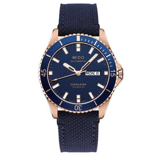 The MIDO Ocean Star 39mm Automatic Watch features a blue face, blue bezel, blue fabric strap, rose gold case, day-date display, luminous markers and hands, and water resistance—blending style and function from MIDO.