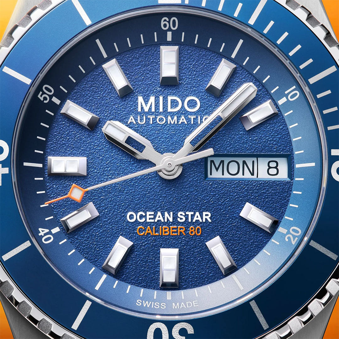 Close-up of the MIDO Ocean Star 200 Automatic 41mm watch, featuring a blue face with luminous hour markers, "MON 8" date display, and silver hands with an orange-tipped seconds hand on this water-resistant MIDO timepiece.