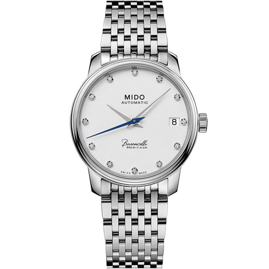 The MIDO Baroncelli III Heritage Lady Automatic 33mm Watch features a silver case, Swiss automatic movement, white dial with diamond hour markers, blue seconds hand, date at 3 o’clock, and a silver link bracelet.