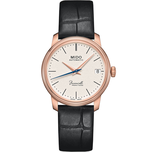 The MIDO Baroncelli III Heritage Lady Automatic 33mm Watch features a white dial, rose gold case, black leather strap, date at 3 o'clock, and simple hour markers—elegance and precision from MIDO.