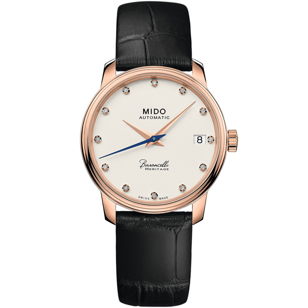 The MIDO Baroncelli III Heritage Lady Automatic 33mm Watch features a white dial, rose gold case, diamond markers, blue second hand, black leather strap, and date at 3—showcasing Swiss elegance.