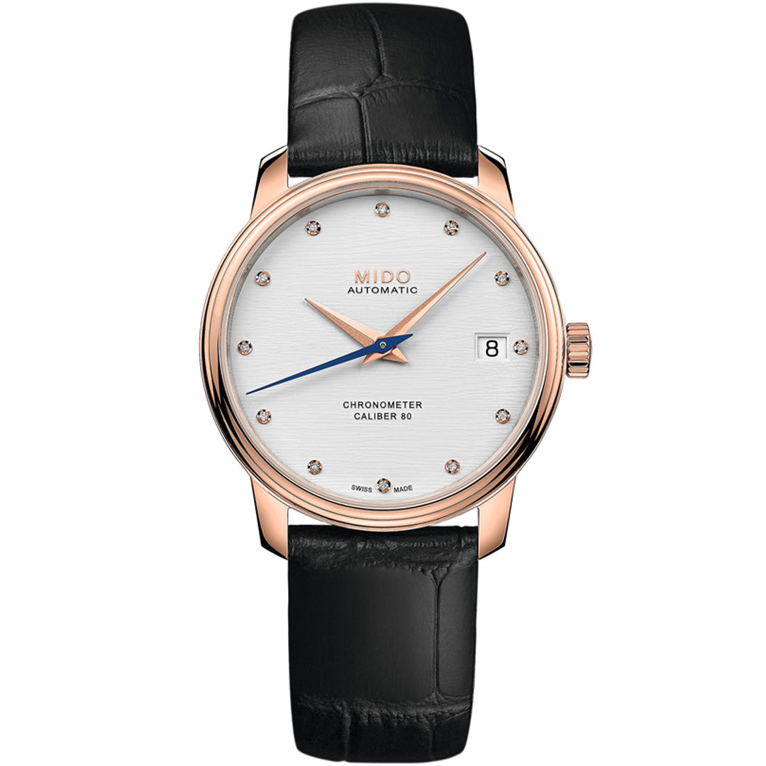 The MIDO Baroncelli III Chronometer Silicon Lady Automatic 34mm features a rose gold case, white dial with diamond markers, date at 3 o’clock, silicon balance-spring movement, and black leather strap. Displays “MIDO AUTOMATIC” and “CHRONOMETER CALIBER 80.”.